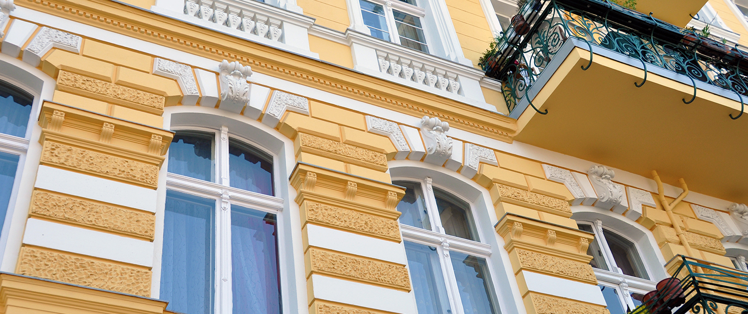 Fassadensanierung historische Fassade – Malerfachbetrieb Binder Historische Fassade in warmem Gelb mit weißen Stuckelementen – hochwertige Fassadensanierung und Renovierung durch Malerfachbetrieb Binder.