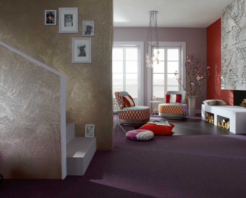 Exklusive Raumgestaltung mit Spachteltechnik & Kaminwand – Malerfachbetrieb Binder Wohnraum mit metallisch schimmernder Spachteltechnik, rosé-grauen Wandflächen, roter Kaminwand und strukturierter Putzoberfläche – gestaltet vom Malerfachbetrieb