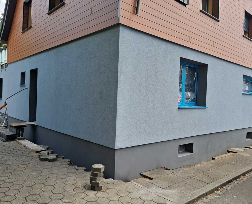 WDVS-Fassadensanierung – Malerfachbetrieb Binder Wärmedämmverbundsystem (WDVS) mit hellgrauer Putzfassade und dunklem Sockel – energetische Fassadensanierung durch Malerfachbetrieb Binder